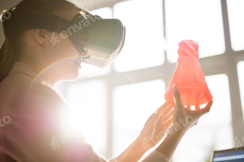 Preview: Young woman in vr headset holding red plastic object in front of her face