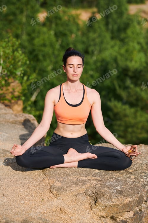 Preview: Concentrated young woman in sportswear sitting with crossed legs