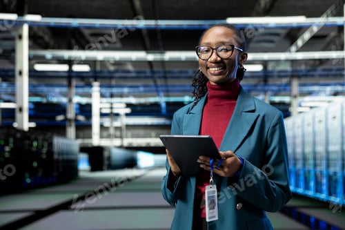 Preview: Portrait of happy female engineer in data center using tablet to monitor rigs