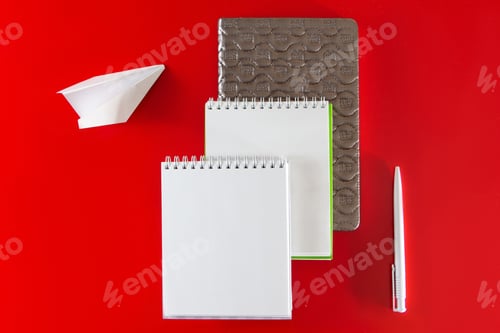 Preview: Minimalistic layout for design. Office supplies - notebooks and pens on a red background.