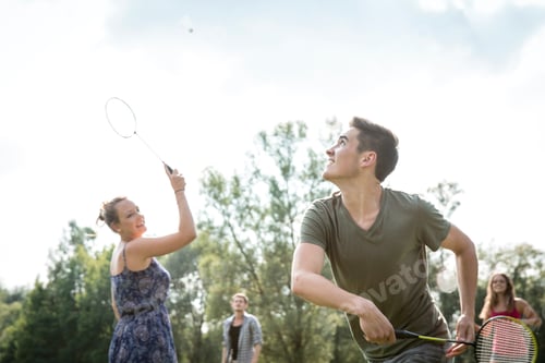 Preview: Group of young adults playing badminton in field