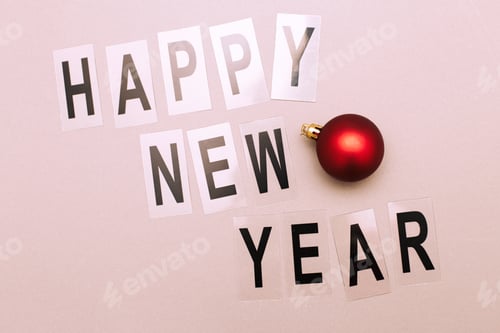 Preview: The inscription happy new year with shiny Christmas toy ball on a pink background.