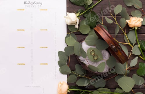 Preview: Wedding rings and paper planning checklist on wooden table