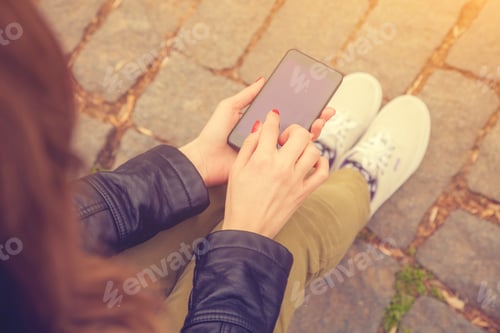 Preview: Girl Sitting On A Bench And Texting On A Cellphone.
