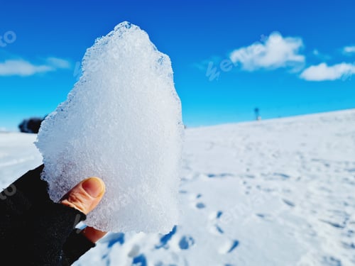 Preview: Shallow focus of man's hand holding a piece of ice with a blurred background