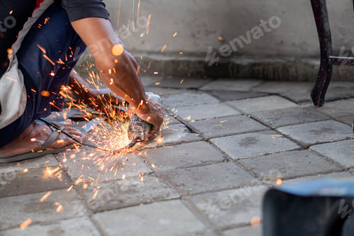 Preview: Worker using angle grinder with flying sparks