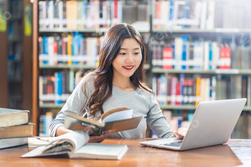 Preview: Asian young Student in casual suit doing homework and using technology laptop in library