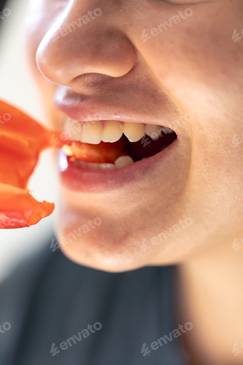 Preview: Detailed shot of a woman bites red bell pepper.