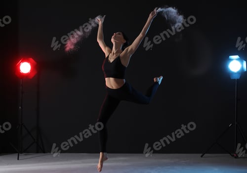 Preview: Professional acrobat with chalk powder exercising in dark studio
