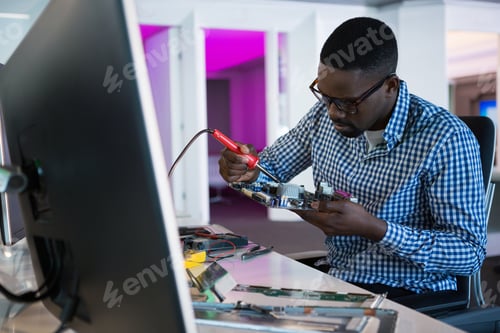 Man Repairing Computer Circuit Board in an Office