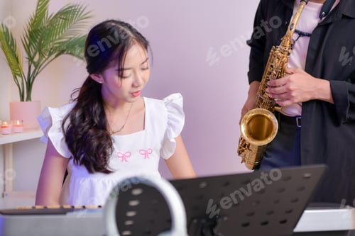 Preview: Two young Asian man and woman performing music indoors with keyboard and saxophone