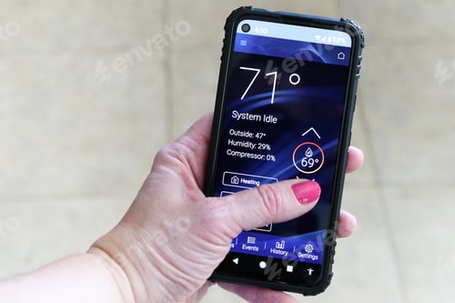 Preview: Female adjusting heating cooling thermostat via an app on her phone. modern technology