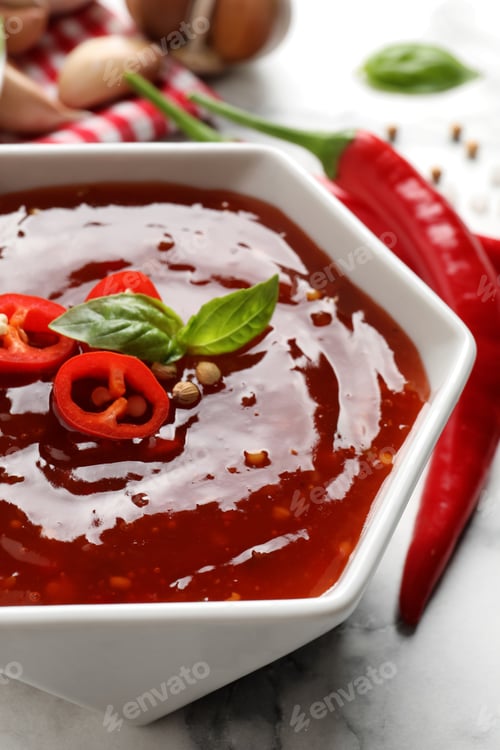 Preview: Spicy chili sauce with basil in bowl on table, closeup
