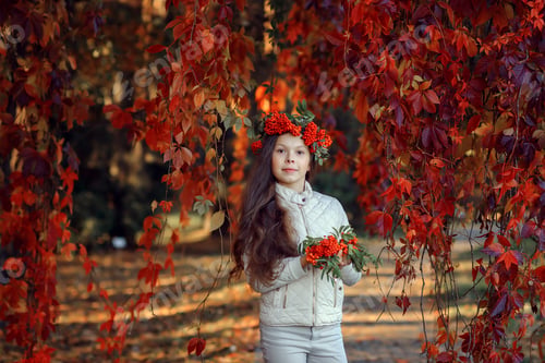 Preview: a girl in a park in a light jacket with a rowan on her head holds maple leaves