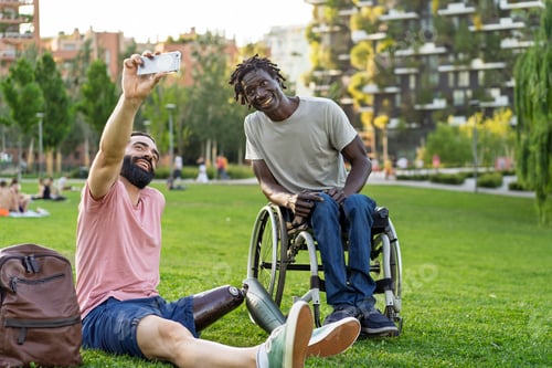 Preview: Two friends with prosthetic leg and wheelchair taking a selfie in the park