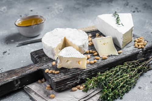 Preview: Delicious cheese brie and camembert on wooden board with herbs and nuts. Dairy French products.