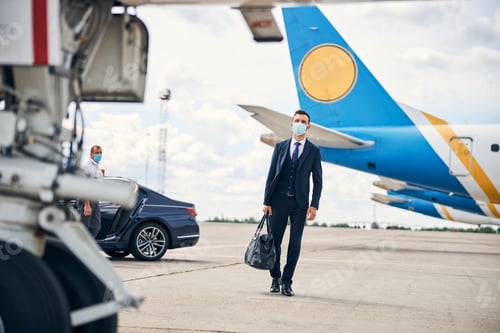 Preview: Modern businessman travelling safely with a mask on