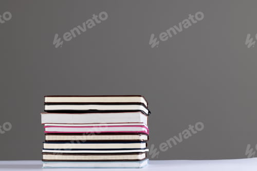 Preview: Close up of stack of books and notebooks with copy space on grey background