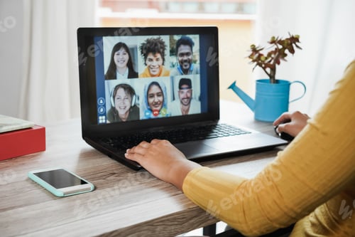 Preview: Young woman having video call with her colleagues using laptop computer app - Focus on left hand