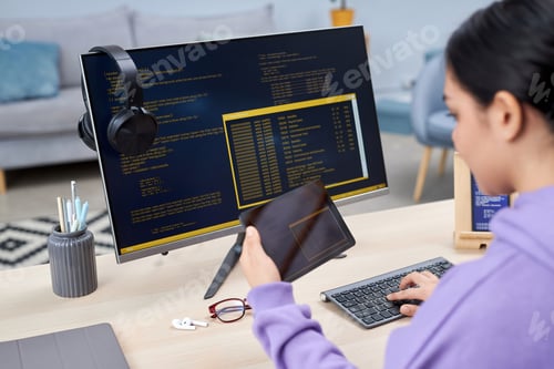 Preview: Female computer programmer writing code for mobile devices at desk