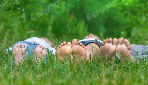 Preview: Children's feet on the green grass in the park. Selective focus.