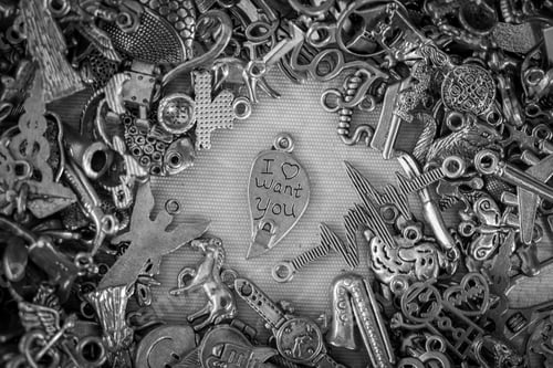 Preview: Top view of a pile of bronze metal pendants with a half heart pendant 'I want you" in the middle