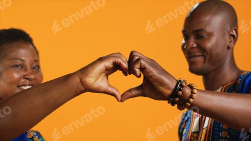 Preview: Ethnic couple in love showing heart shape sign and kissing