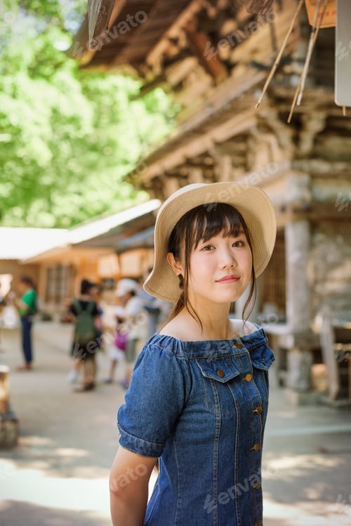Preview: Young woman wearing blue dress and hat at Shinto Sakurai Shrine, Fukuoka, Japan.
