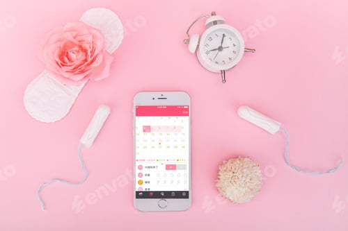 Preview: Flat lay shot of a sanitary pad, tampons, an alarm clock and a smartphone with a calendar opened