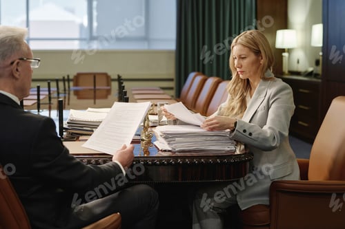 Preview: Female and Male Jurists Reading Papers from Pile on Office Table