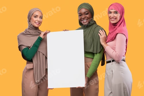 Preview: Three Muslim Ladies In Hijab Holding Empty Poster, Yellow Background