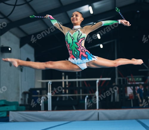 Preview: Sports, gymnastics and woman jumping with a ribbon in a professional gym or arena for training. Fit