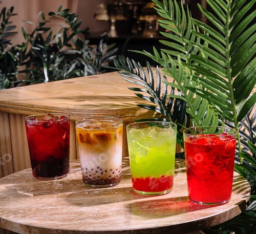 Preview: Four colorful summer cocktails resting on a stone tabletop in a tropical setting