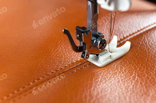 Preview: Modern sewing machine presser foot with a needle sews brown leather