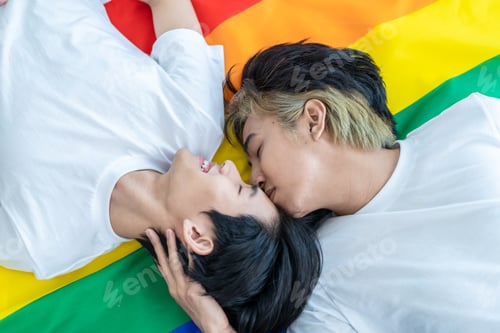 Preview: Asian man gay family lying down on LGBT flag and look at each other, sleep on bed in bedroom