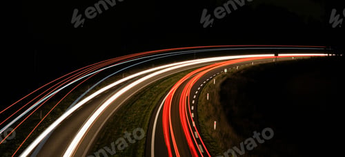 Preview: Aerial long-exposure view of car light trails on a highway road at night