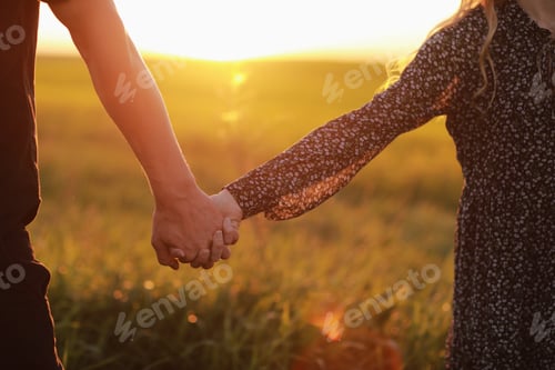 Preview: Couple hold hands in the autumn or summer park on sunset. Closeup of loving couple holding hands w