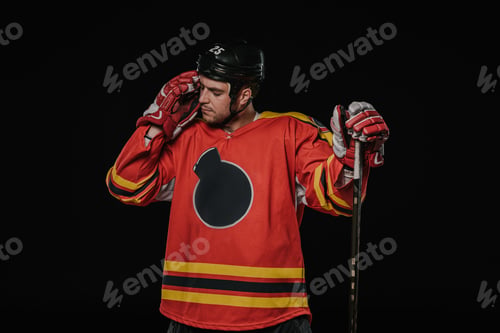 Preview: tired hockey player standing with hockey stick isolated on black