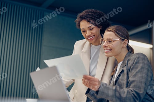 Preview: Two smiling business woman work together with documents to get the job done at the