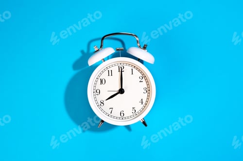 Preview: White alarm clock on a blue background isolated, top view.