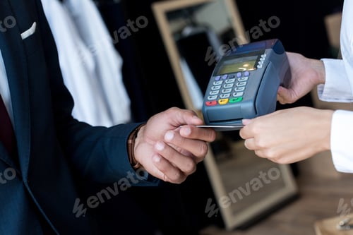 Preview: cropped shot of businessman paying by credit card and terminal in boutique
