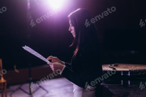 Preview: Female Musician Reading Sheet Music Understage Lighting Inside A Dark Performance Venue