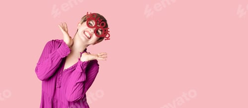Preview: A cheerful young woman in Christmas glasses poses on a highlighted pink background.