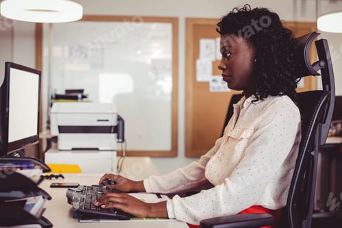 Preview: African American woman typing at office desk in office attire with keyboard, monitor, copy space