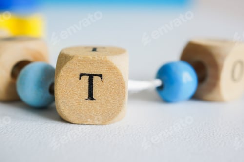 Preview: Closeup shot of letter T on a wooden cube bead with a blurred background