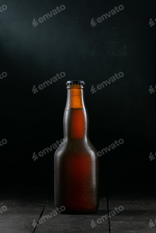Preview: Vertical closeup shot of a brown glass bottle on a wooden table with a black background