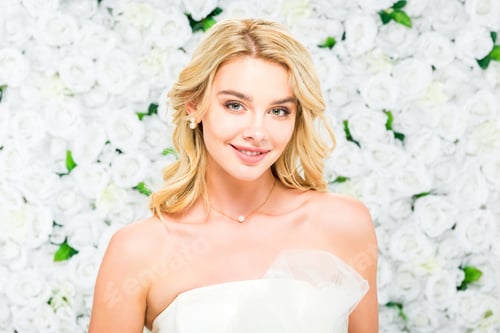 Preview: smiling pretty young woman with blonde hair looking at camera on white floral background