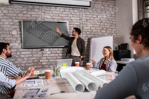 Preview: Group of modern business people in casual wear discussing architectural designs in the office.