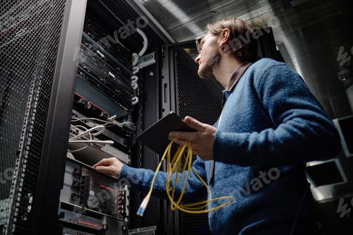 Preview: Adult Caucasian Man Managing Server Equipment in Data Center Room