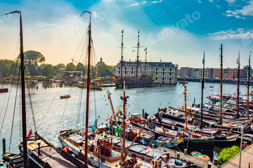 Preview: Stunning shot of many moored sailboats with Amsterdam modern traditional buildings in the background